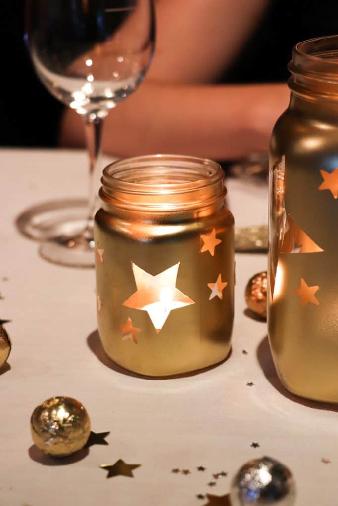 Gold jars with stars and tea light candles. Christmas table decor.