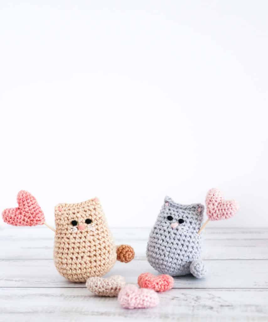 two crochet cats holding crochet hearts 