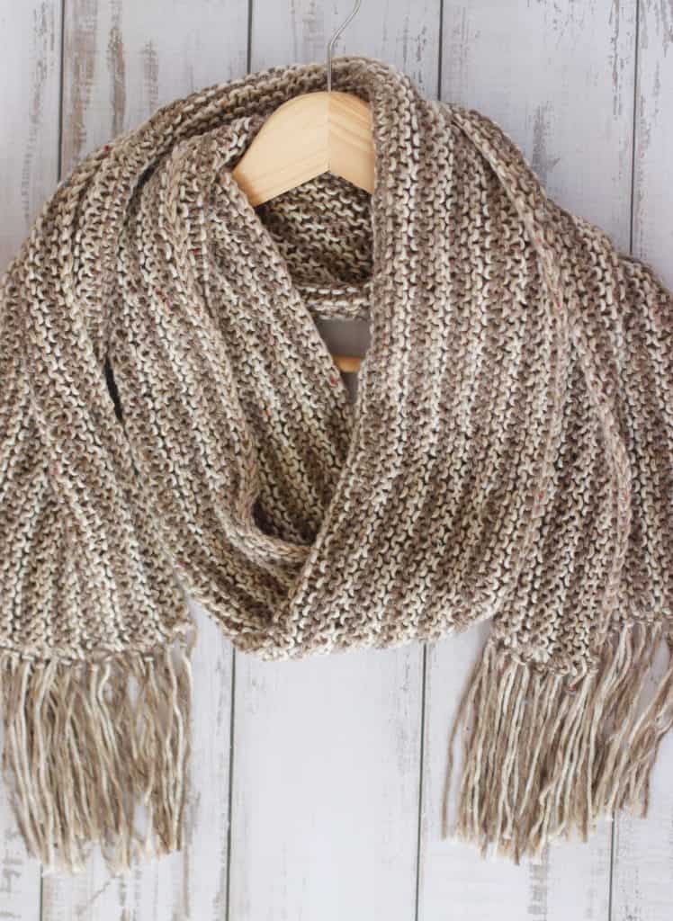 knitted scarf in brown and cream yarn on a wooden hanger