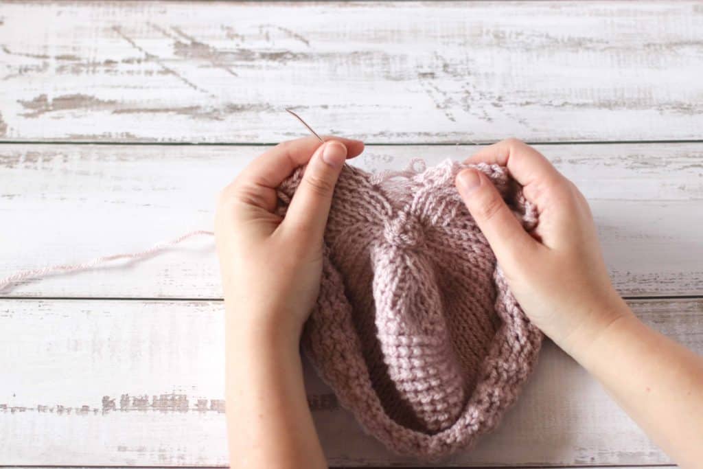 How to crochet a Tunisian crochet baby hat. Hands showing where to place a need in a crocheted hat.