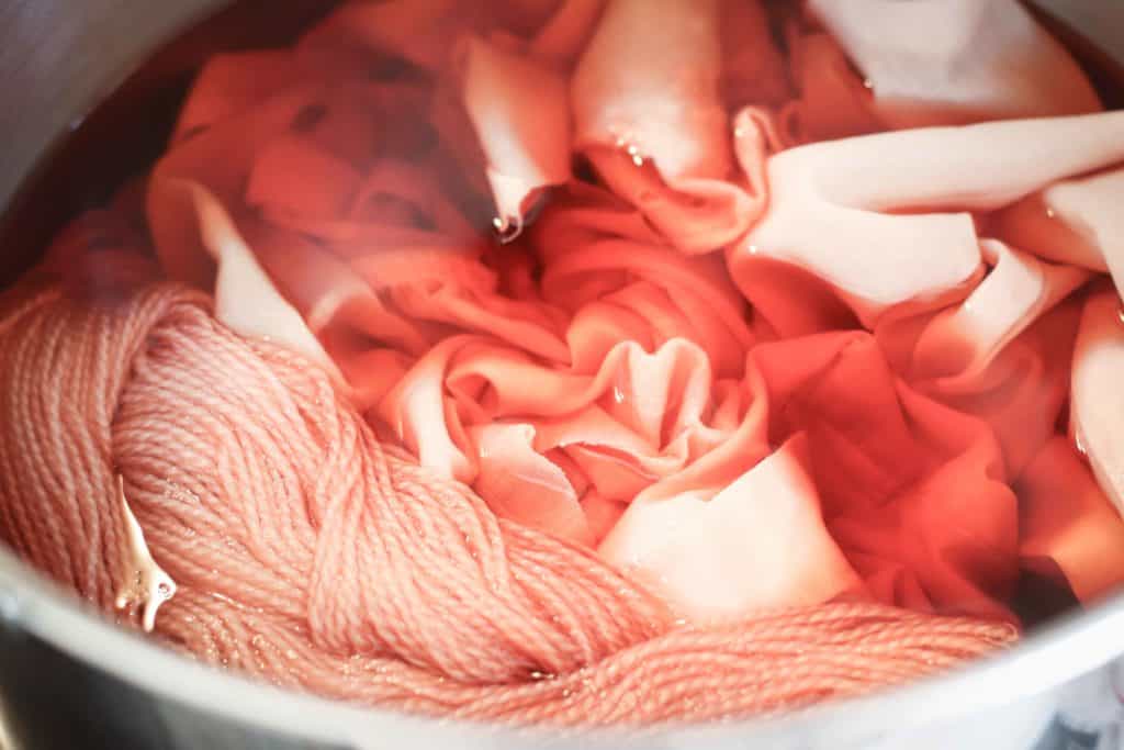 Yarn and cotton fabric sitting in a pink dye bath