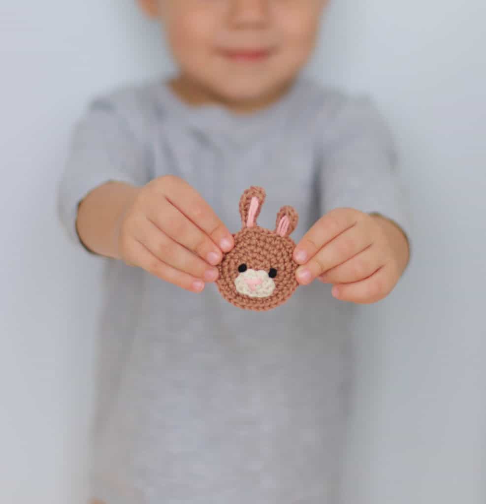 a brown crochet bunny applique held by a small boy, bunny applique crochet pattern