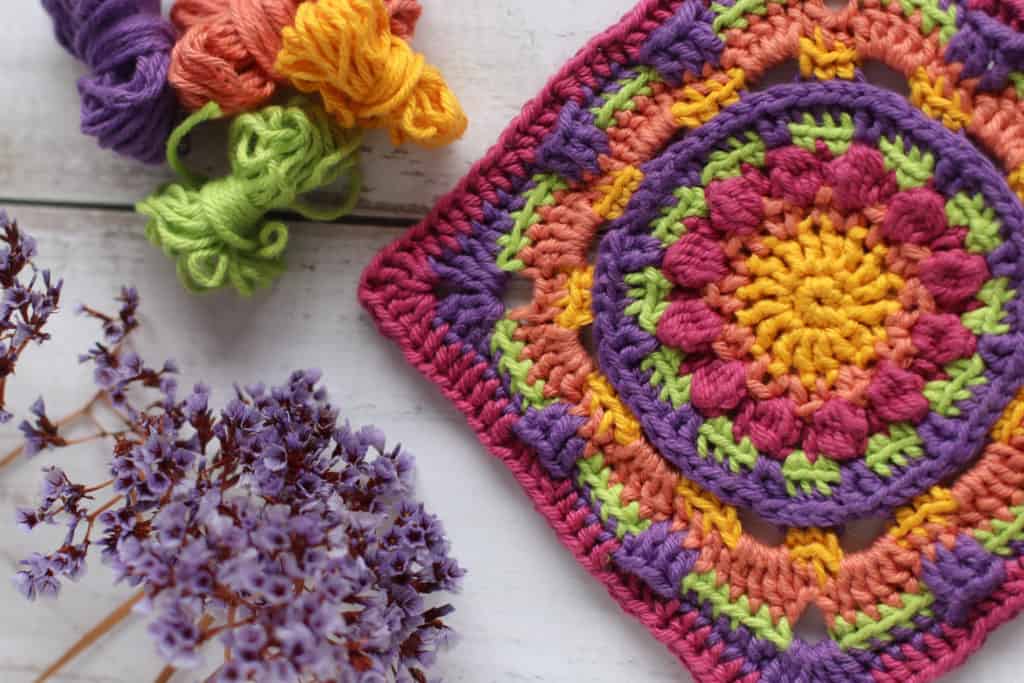 Brightly coloured crochet square, in orange, purple, pink and yellow