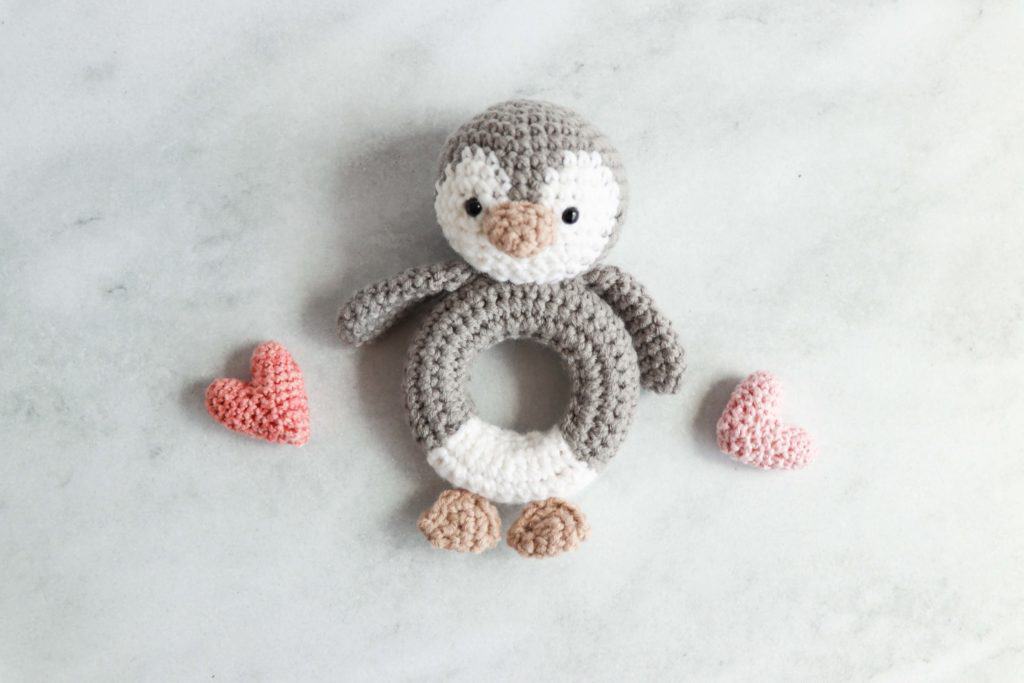 crochet penguin rattle flanked by two pink crochet hearts