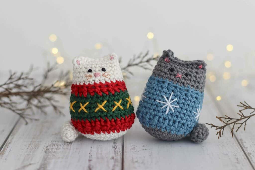 Crochet cat pattern, two crocheted cats wearing festive sweaters, surrounded by fairy lights