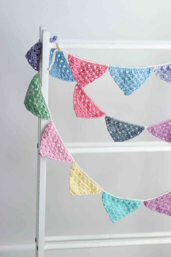 Granny stitch crochet bunting pattern Brightly colored crochet bunting hanging on a wooden stand